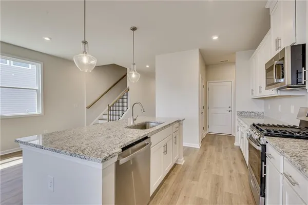 a kitchen with stainless steel appliances granite countertop a sink a stove and a wooden floors