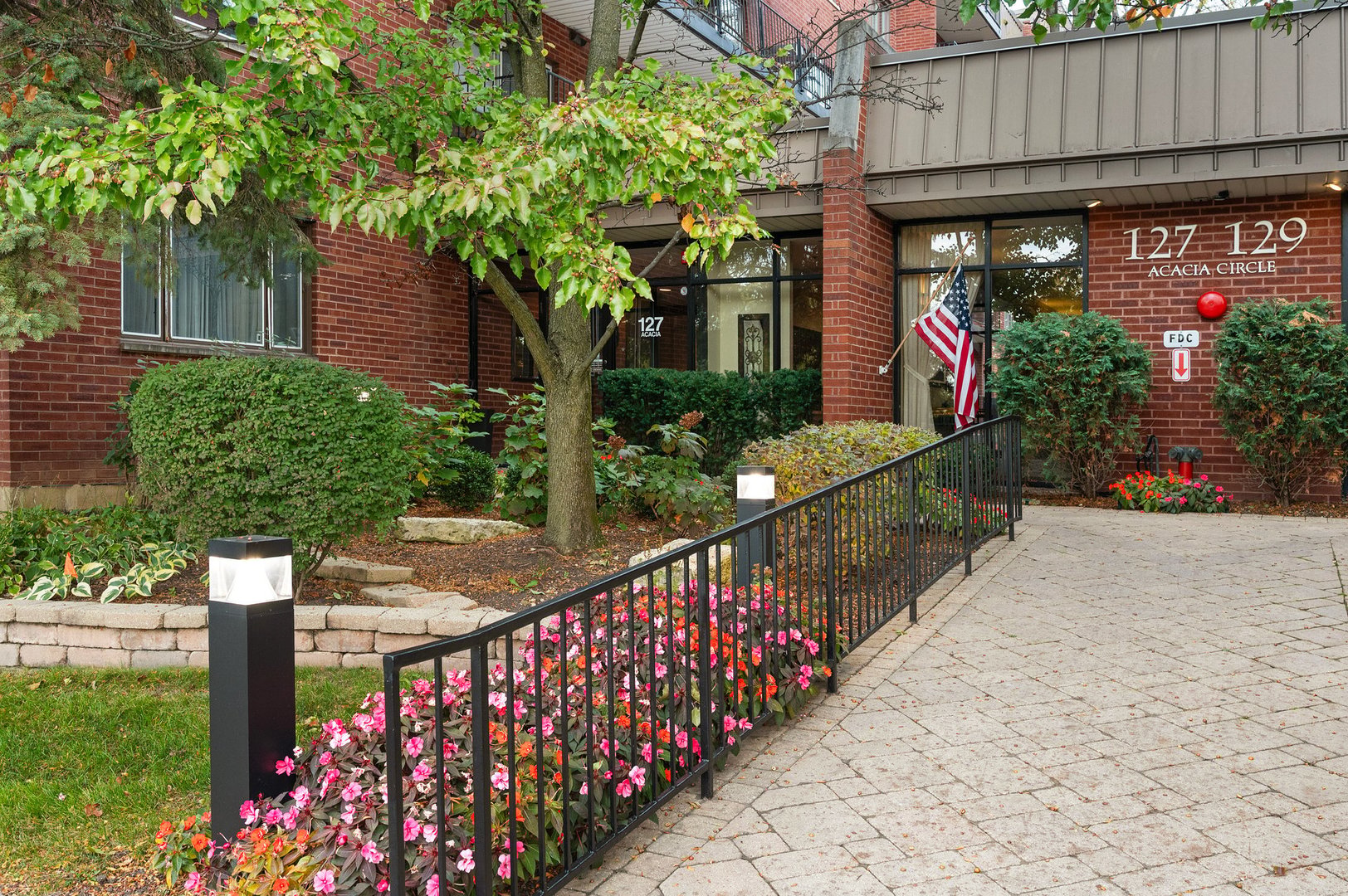 a couple of flower plants sitting in front of yellow house