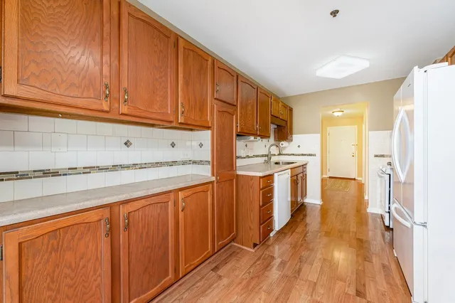 a kitchen with stainless steel appliances granite countertop a refrigerator a sink dishwasher and wooden cabinets with wooden floor