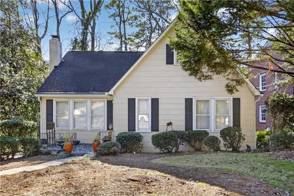 a view of a brick house with a yard plants and large tree