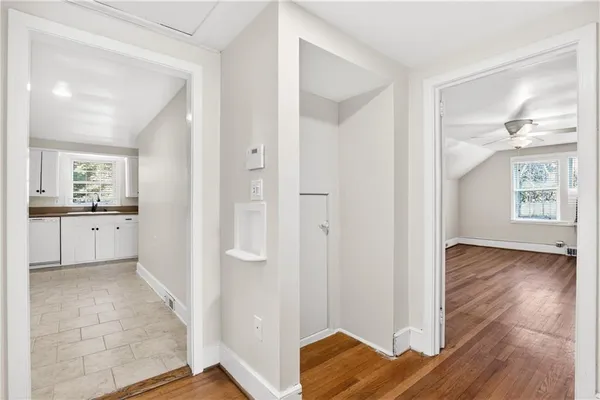 a view of a kitchen from a hallway with wooden floor and a bathroom
