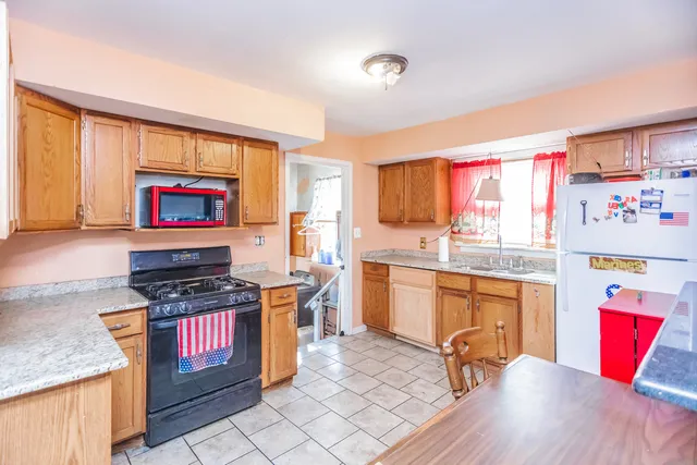 a kitchen with stainless steel appliances granite countertop a stove top oven a sink dishwasher and a dining table with wooden floor