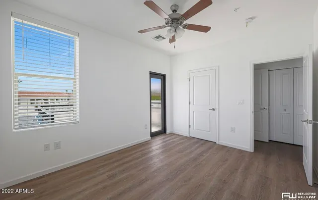 a view of an empty room with wooden floor and a window