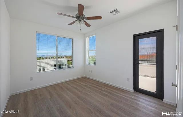 a view of an empty room with a window and wooden floor