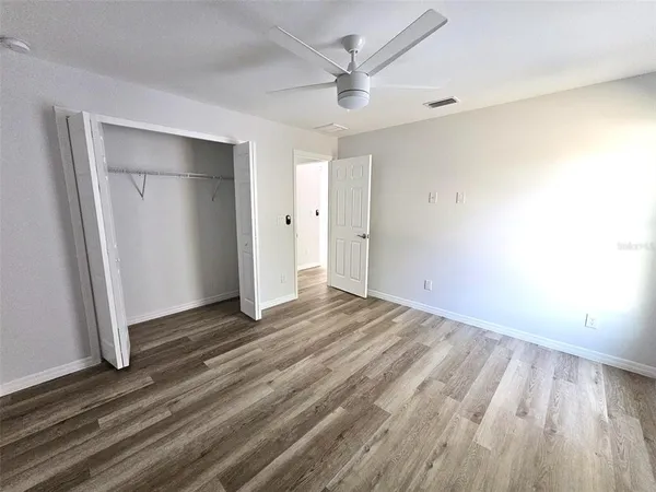 an empty room with wooden floor and a ceiling fan