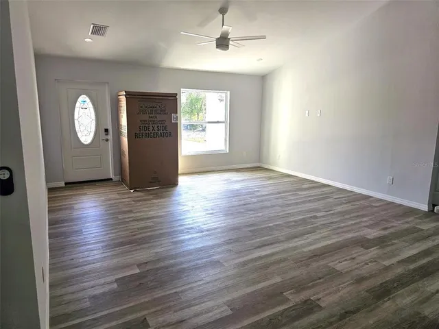 an empty room with wooden floor and windows