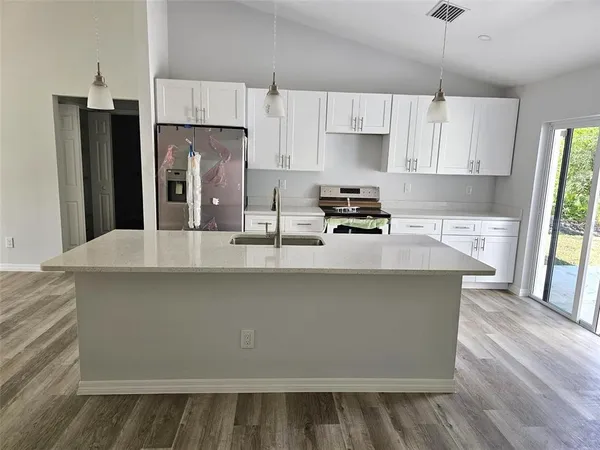 a kitchen with stainless steel appliances a refrigerator a sink a stove a microwave and wooden floors