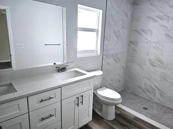 a bathroom with a granite countertop sink a toilet and a shower