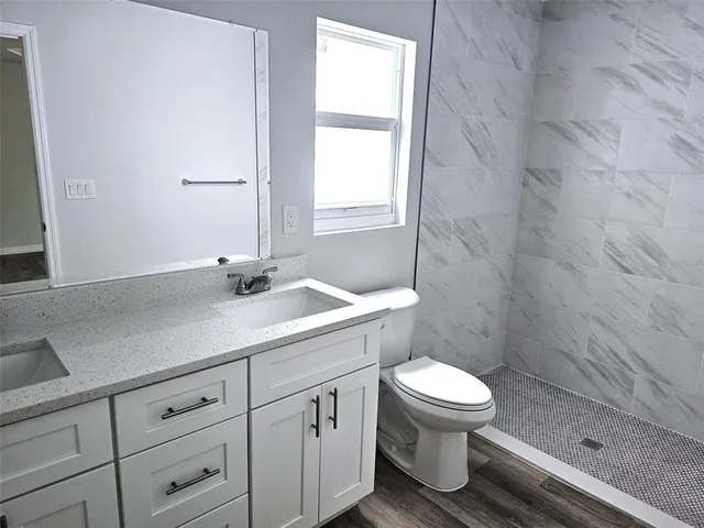 a bathroom with a granite countertop sink a toilet and a shower