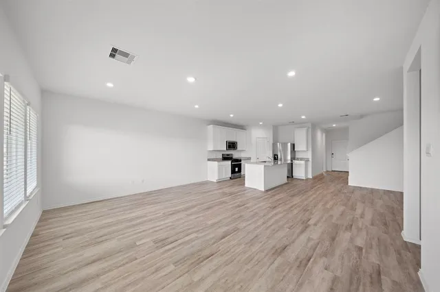 a view of empty room with wooden floor and window