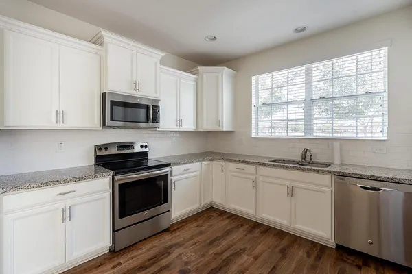 an empty room with wooden floor ceiling fan and windows
