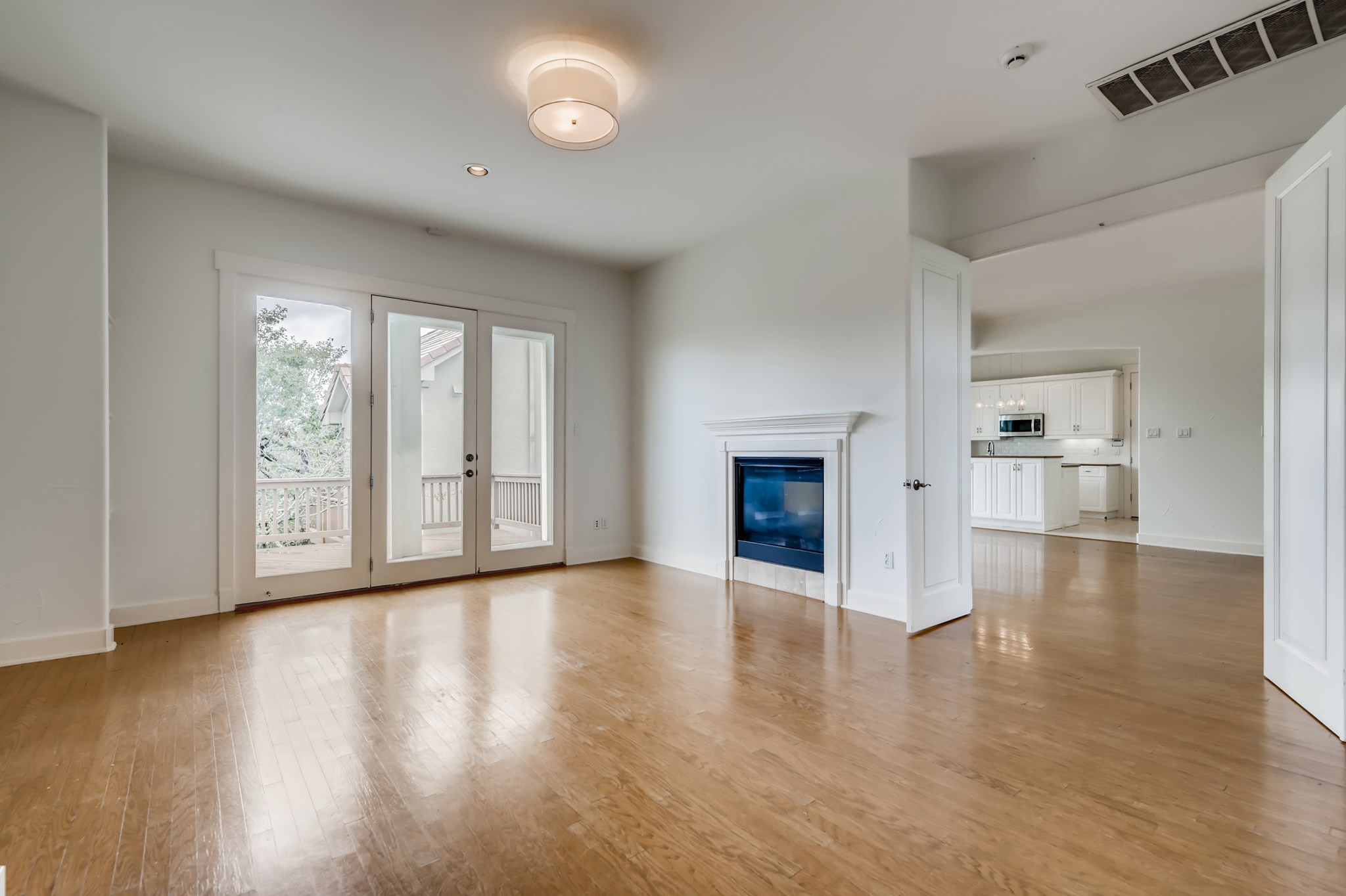 2800 Waymaker Way, Unit 27 Austin, TX 78746 - Photo 3 of 17 Unfurnished living room with french doors, a glass covered fireplace, and light wood-type flooring