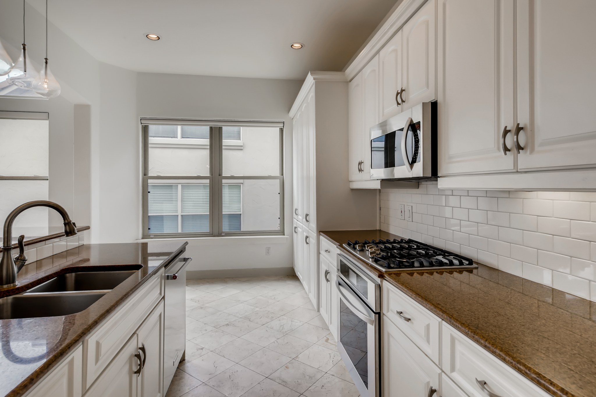 2800 Waymaker Way, Unit 27 Austin, TX 78746 - Photo 6 of 17 Kitchen featuring dark stone counters, stainless steel appliances, white cabinetry, and pendant lighting