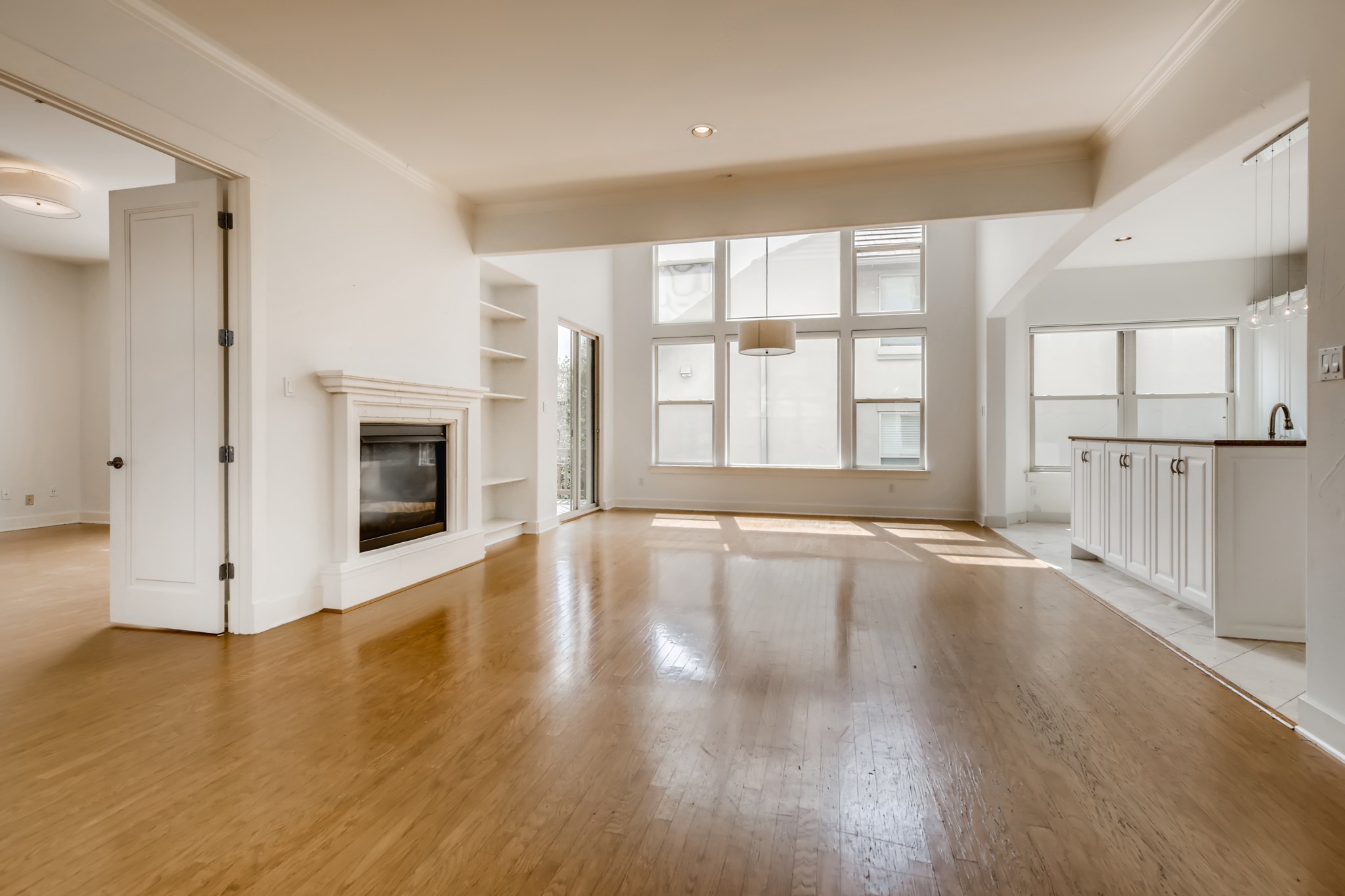 2800 Waymaker Way, Unit 27 Austin, TX 78746 - Photo 7 of 17 Unfurnished living room featuring crown molding, a glass covered fireplace, built in features, light wood finished floors, and recessed lighting