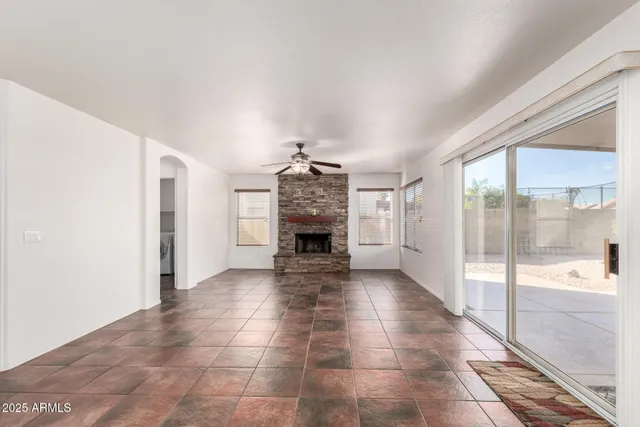 a view of a hallway to an empty room with a fireplace and a window