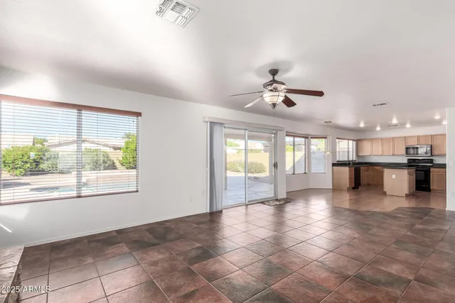 a view of an empty room with a window and kitchen view