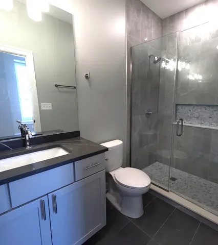 a bathroom with a granite countertop sink a toilet a mirror and shower