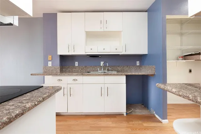 a kitchen with granite countertop a sink a stove and cabinets