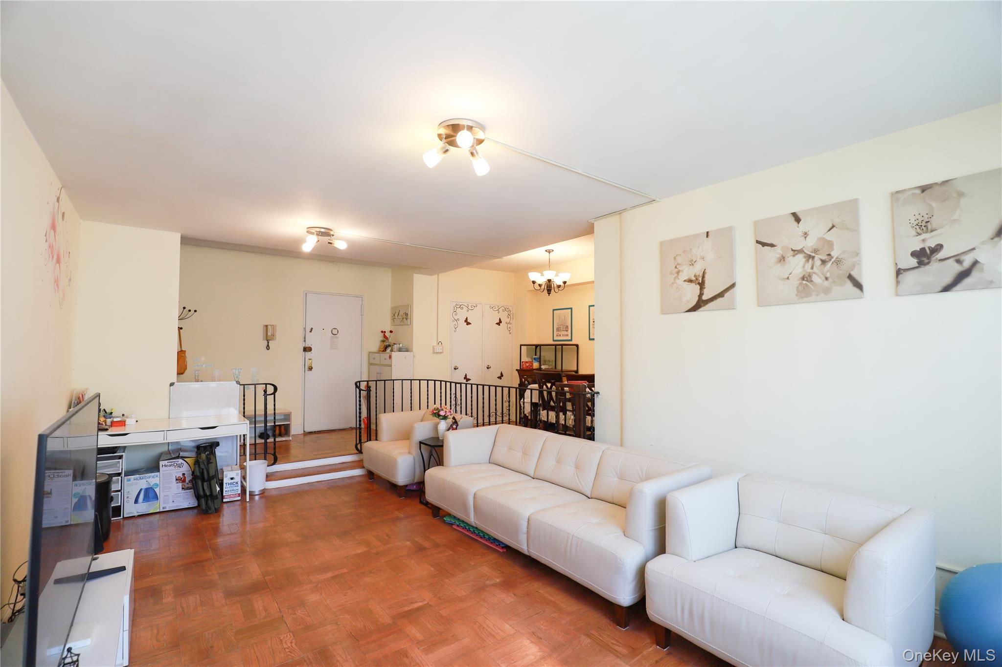 98-25 64th Road, Unit 6F Queens, NY 11374 - Photo 3 of 12 Spacious living area featuring wood-finish flooring, recessed lighting, and a defined dining space with a chandelier