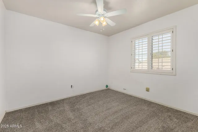 an empty room with a window and a fan