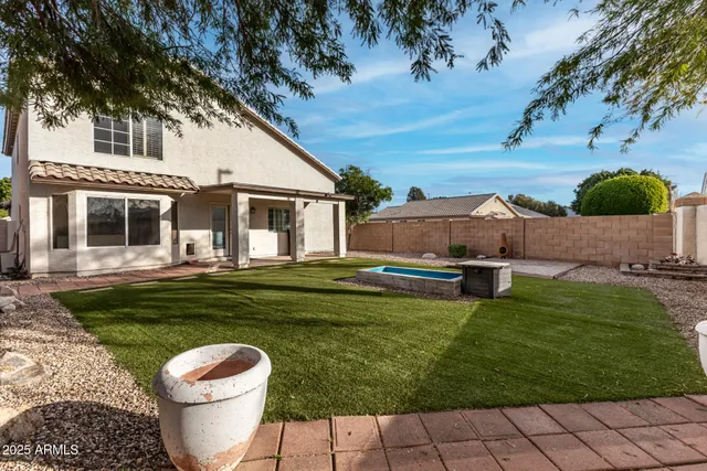 a view of a white house with a yard potted plants and a large tree