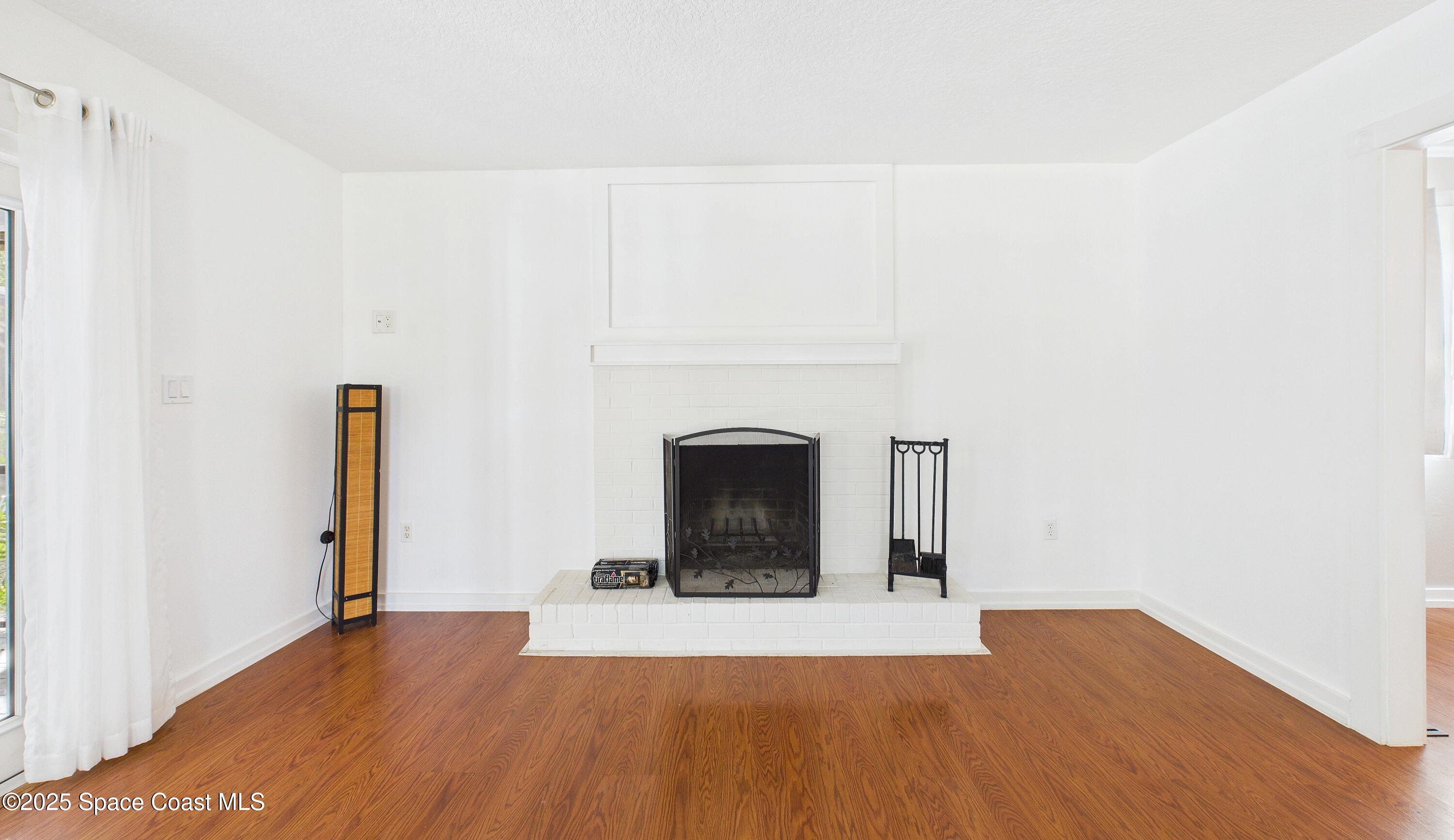 3435 Huggins Drive Malabar, FL 32950 - Photo 13 of 63 a view of empty room with a fireplace and wooden floor