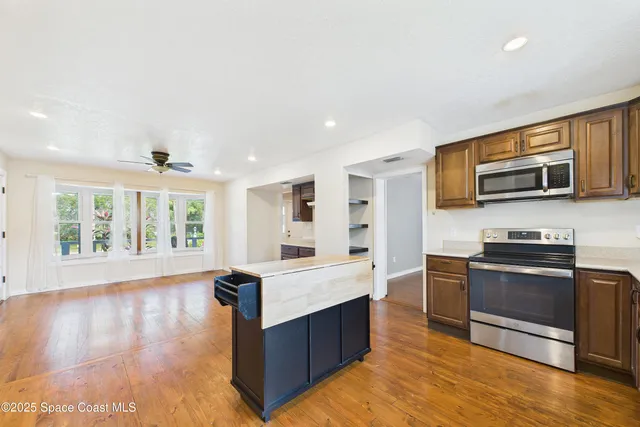 an empty room with wooden floor fan and windows