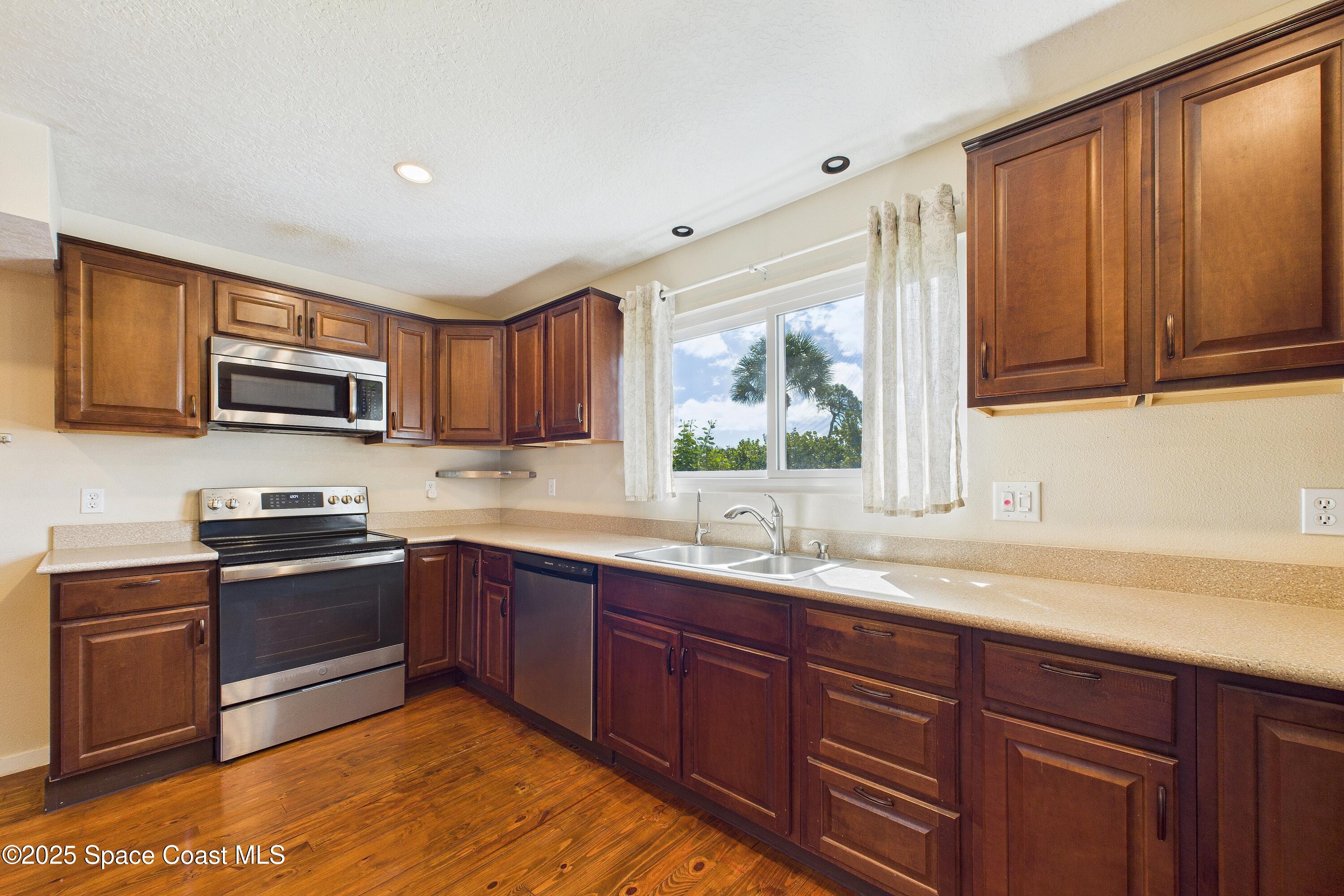 3435 Huggins Drive Malabar, FL 32950 - Photo 24 of 63 a kitchen with stainless steel appliances granite countertop wooden cabinets a stove top oven a sink and dishwasher with wooden floor