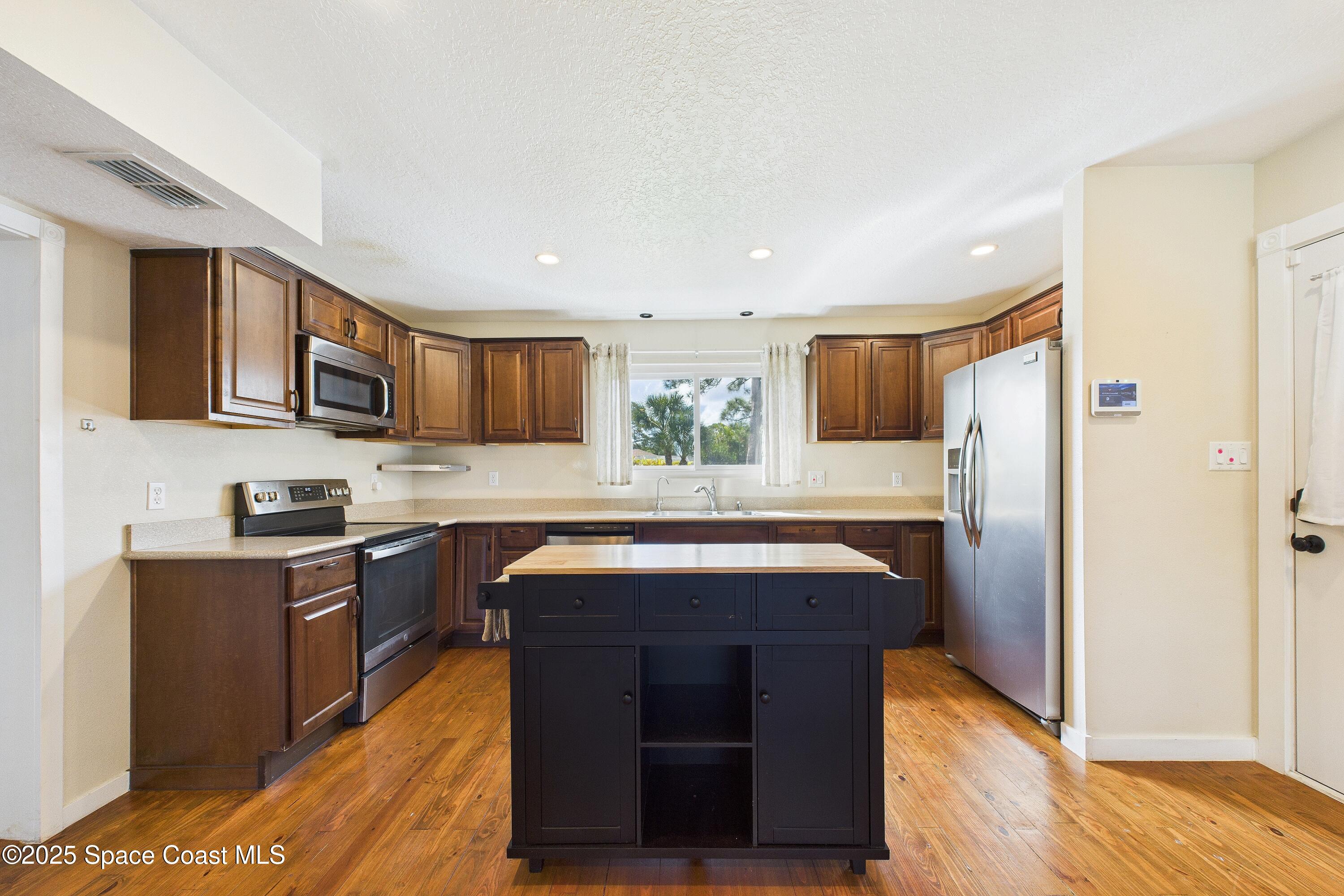 3435 Huggins Drive Malabar, FL 32950 - Photo 25 of 63 a kitchen with stainless steel appliances granite countertop a sink stove and refrigerator