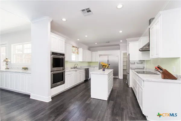 a kitchen with stainless steel appliances a refrigerator sink and white cabinets