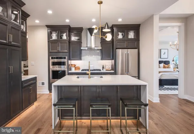 a kitchen with stainless steel appliances kitchen island granite countertop a dining table chairs sink and cabinets