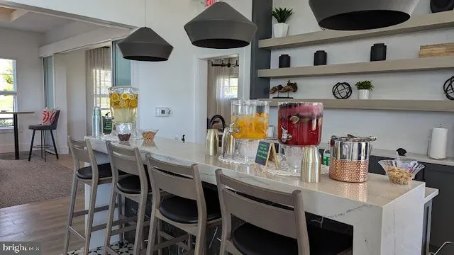 a room with stainless steel appliances kitchen island granite countertop a table chairs in it and wooden floor