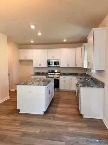 a large kitchen with stainless steel appliances granite countertop a stove a sink and a microwave