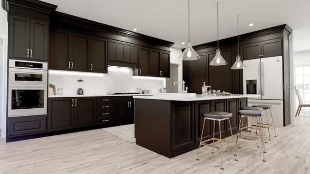 a kitchen with stainless steel appliances kitchen island granite countertop a refrigerator and a sink