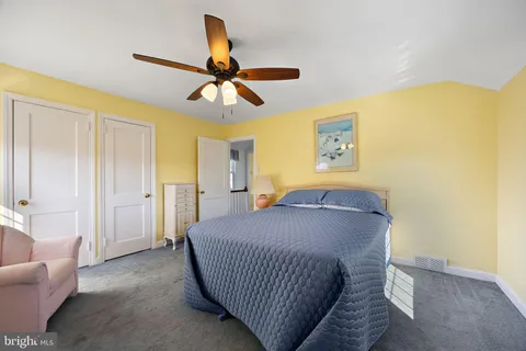 a living room with a bed furniture and a ceiling fan