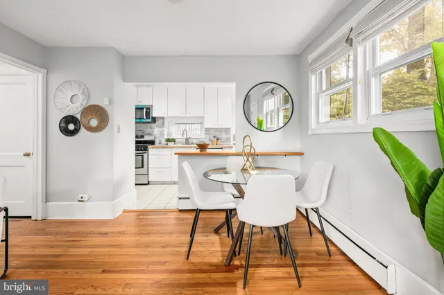 a living room with stainless steel appliances kitchen island granite countertop a dining table chairs and a large window