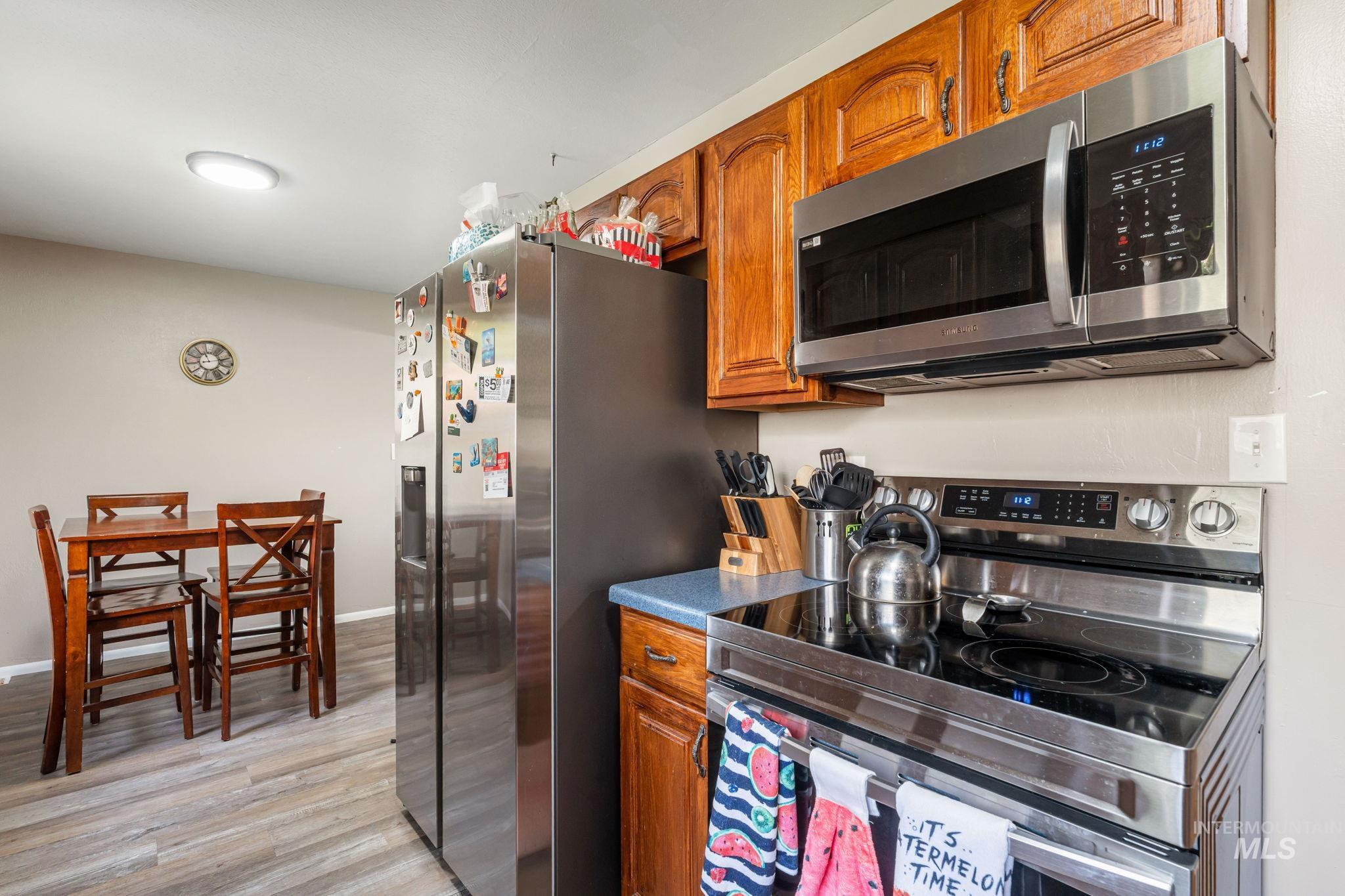 816 Park Lane Pocatello, ID 83201 - Photo 12 of 48 Kitchen featuring appliances with stainless steel finishes, brown cabinets, light wood-type flooring, and dark countertops