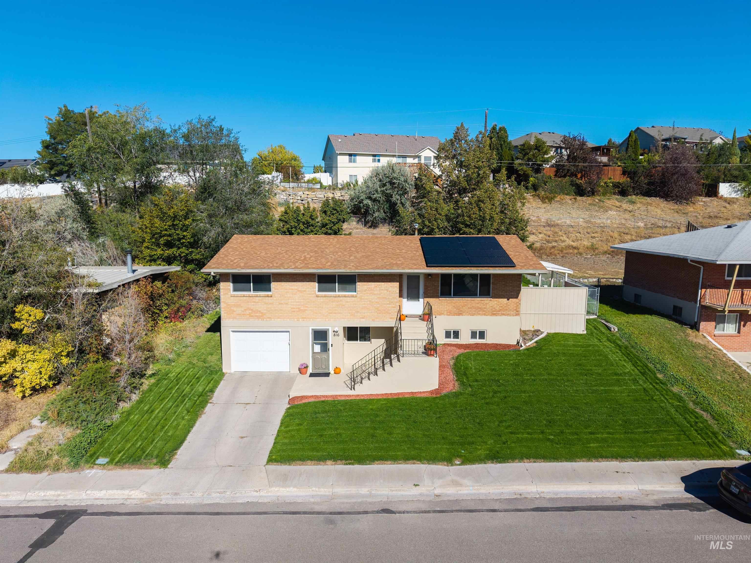 816 Park Lane Pocatello, ID 83201 - Photo 2 of 48 View of front of house with concrete driveway, a front lawn, roof mounted solar panels, brick siding, and a residential view