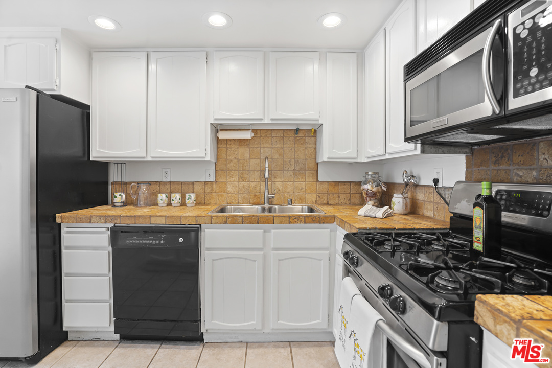 8135 Redlands Street, Unit 101 Playa del Rey, CA 90293 - Photo 12 of 42 a kitchen with stainless steel appliances granite countertop a stove top oven a sink dishwasher and a refrigerator with wooden cabinets