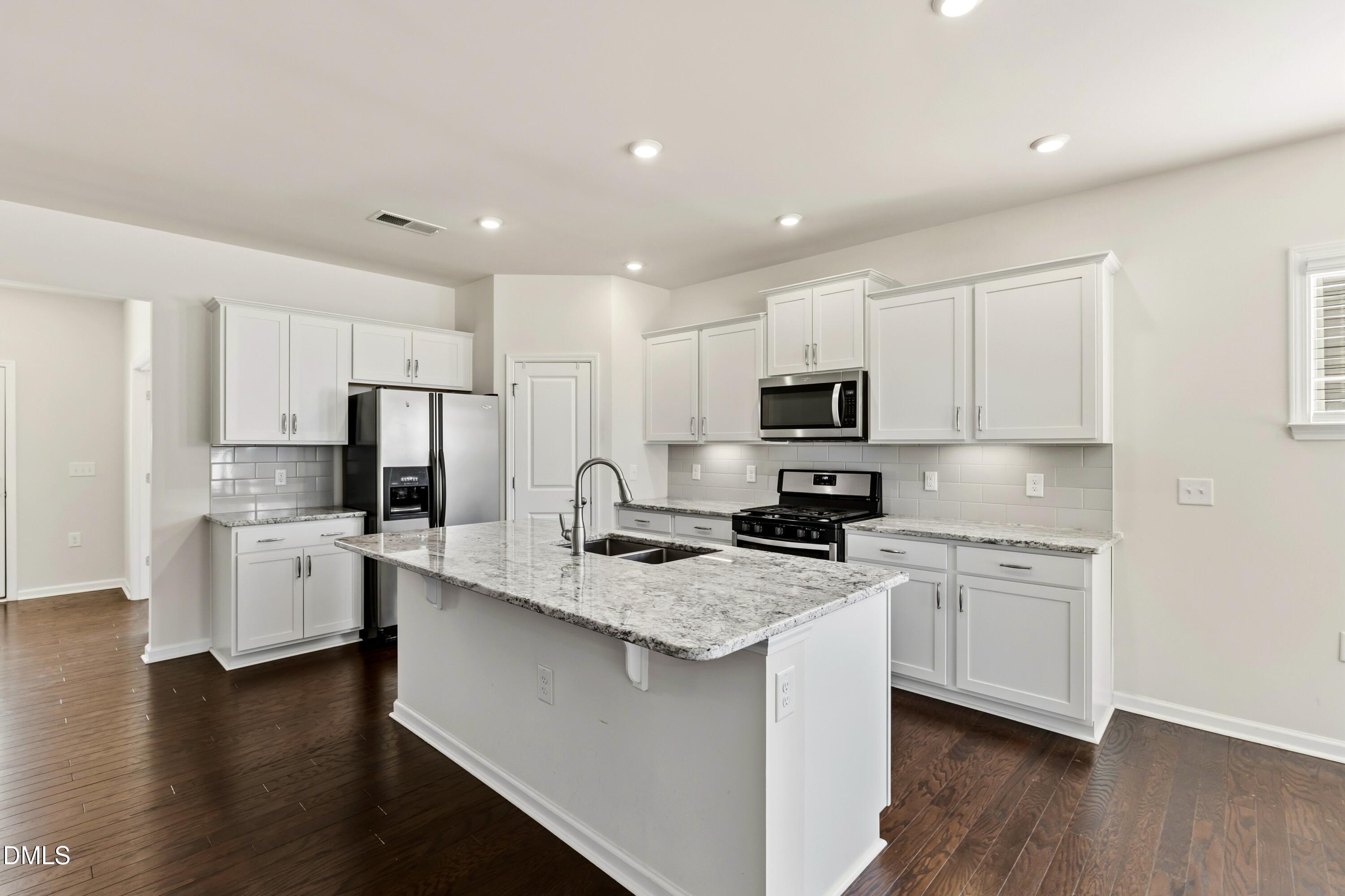 1018 Flyfish Avenue Durham, NC 27703 - Photo 14 of 54 a kitchen with stainless steel appliances granite countertop a stove top oven a refrigerator a sink and dishwasher with wooden floor