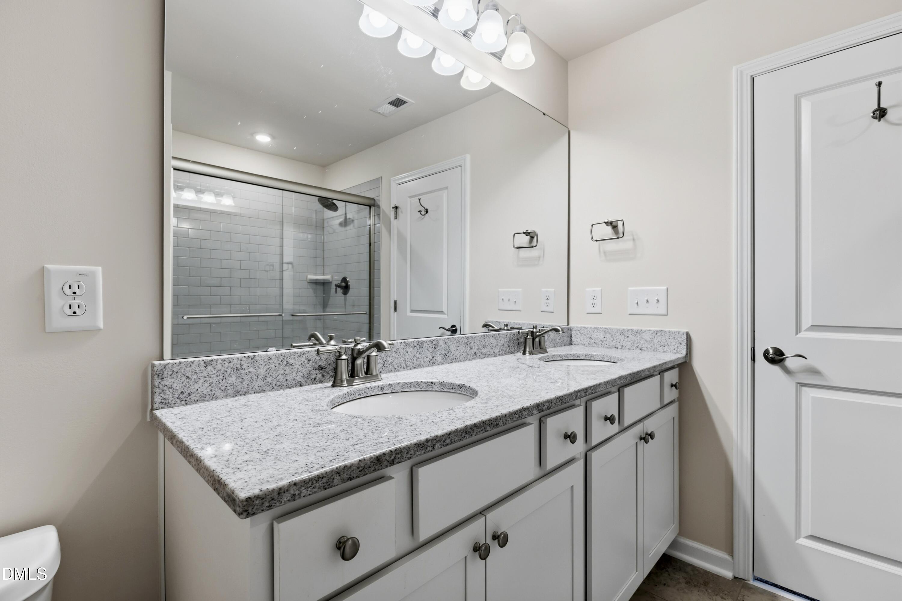 1018 Flyfish Avenue Durham, NC 27703 - Photo 41 of 54 a bathroom with a granite countertop sink a large mirror and shower