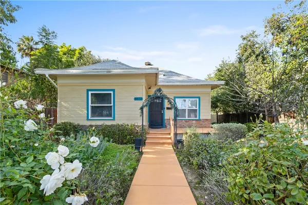 a front view of a house with a yard and potted plants