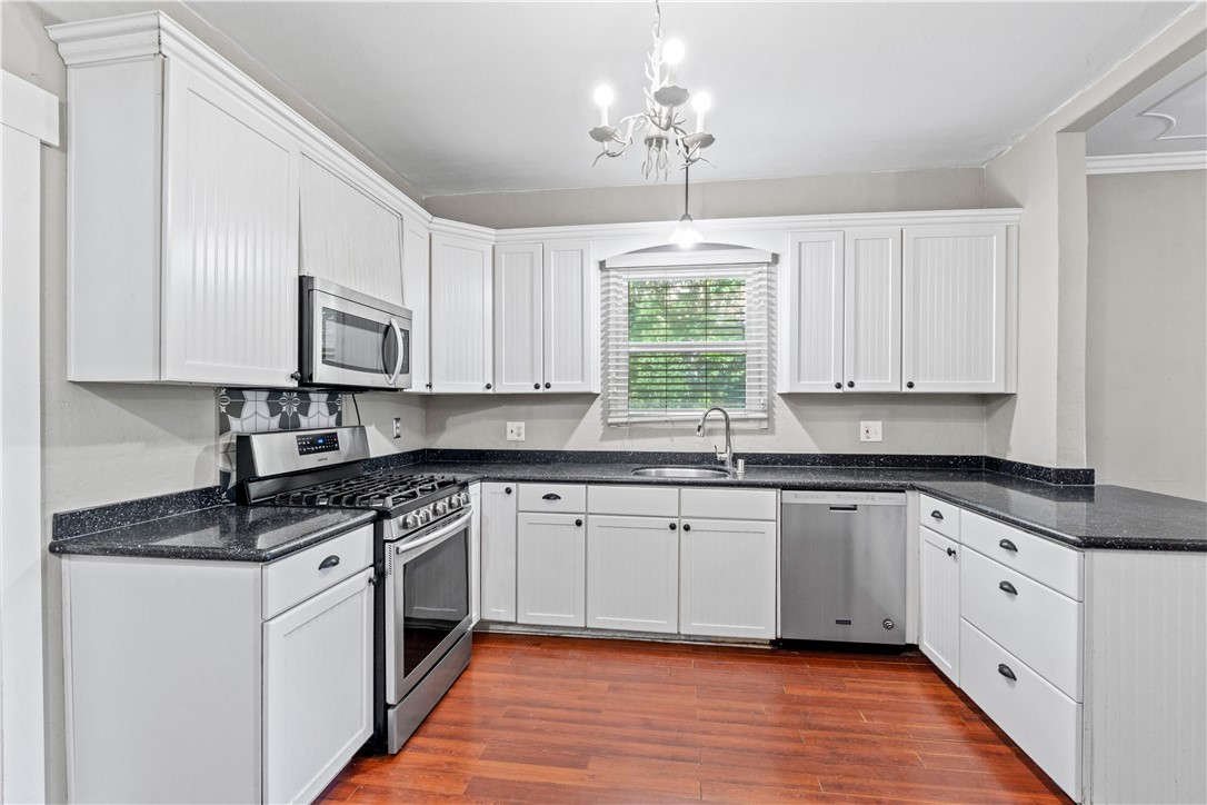 4073 Cedar Street Riverside, CA 92501 - Photo 24 of 46 a white kitchen with stainless steel appliances granite countertop a stove a sink dishwasher and white cabinets with wooden floor