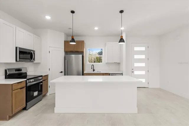 a large kitchen with stainless steel appliances kitchen island a large counter top and a stove top oven