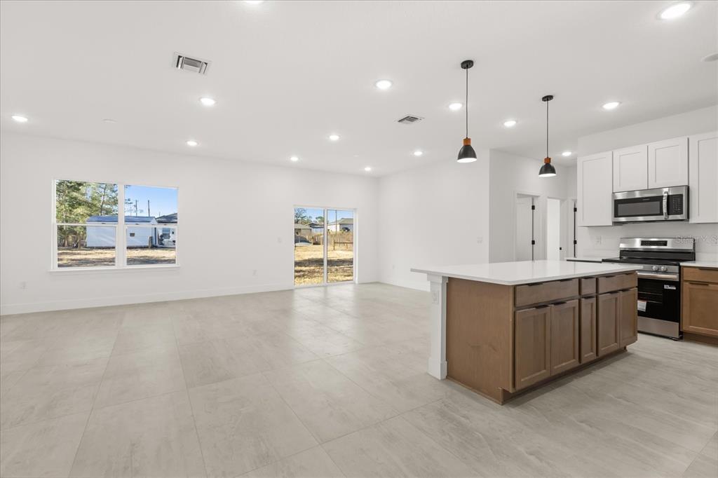 6168 Southwest 154th Street Ocala, FL 34473 - Photo 14 of 33 a large kitchen with stainless steel appliances kitchen island a large counter top and a stove top oven
