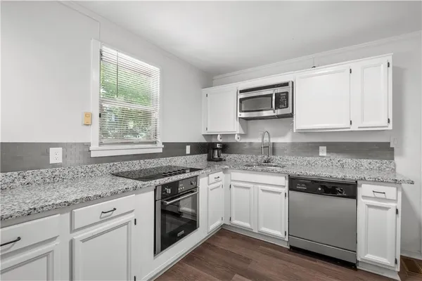 a kitchen with granite countertop stainless steel appliances white cabinets granite counter tops and a wooden floors