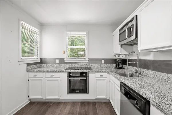 a kitchen with granite countertop stainless steel appliances white cabinets and a granite counter tops