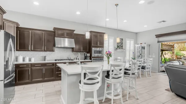 a kitchen with stainless steel appliances granite countertop a stove top oven a sink dishwasher a dining table and chairs with wooden floor