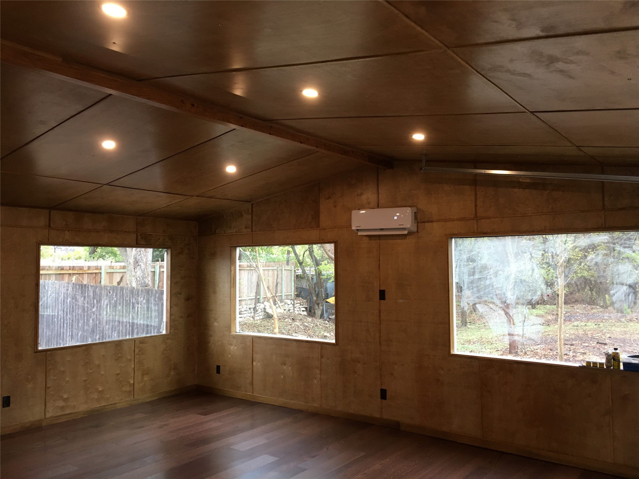 5405 Hudson Street Austin, TX 78721 - Photo 32 of 37 Recessed lighting illuminates the rich wood flooring and paneled walls, creating a warm, inviting space.