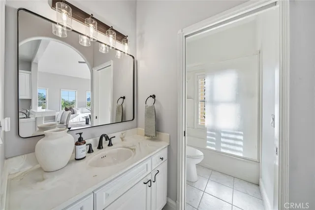 a bathroom with a granite countertop sink a toilet and a mirror